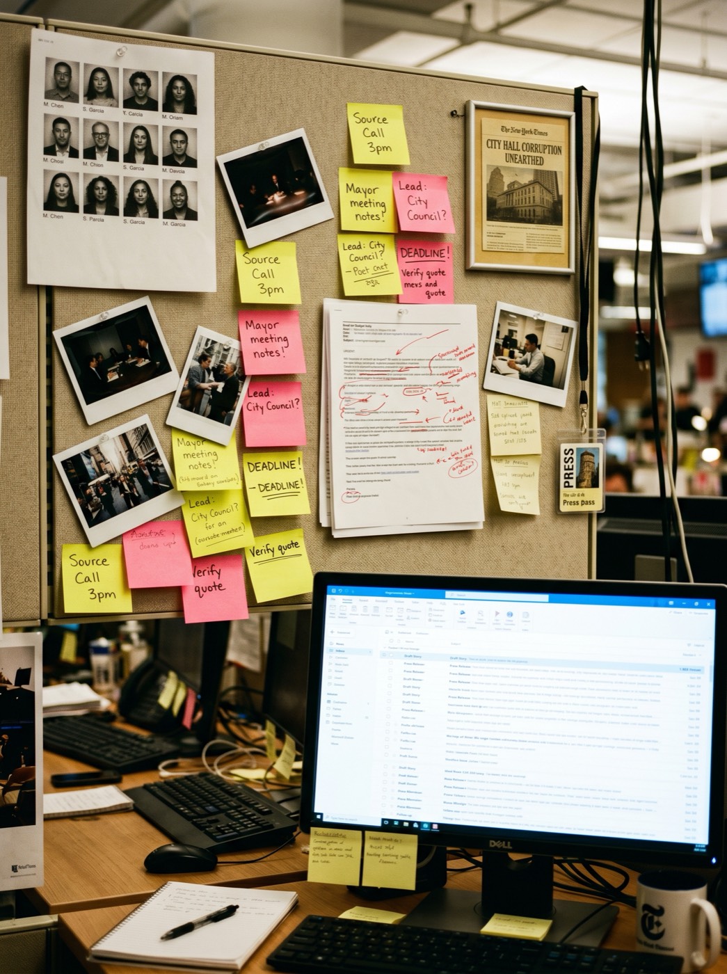 Journalist cubicle wall covered in post-its, polaroids and an open email inbox